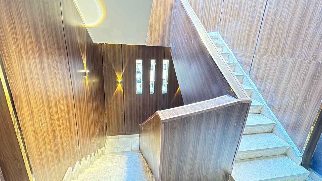 Eine Holztreppe mit modernem Design, die zu einer Empfangshalle mit Glastür führt.