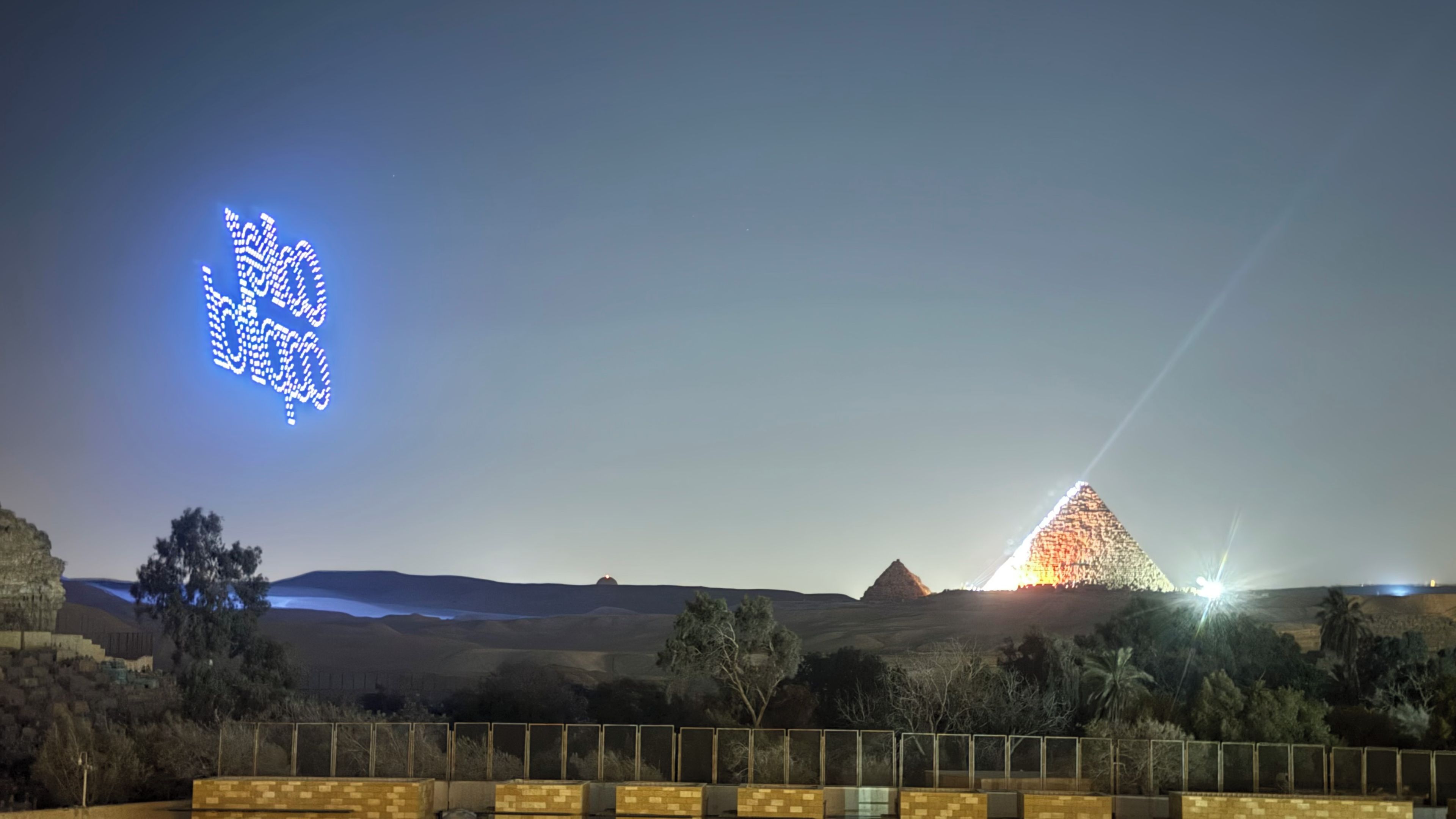 Ett landskap med en pyramid och en pixelerad ljusinstallation.