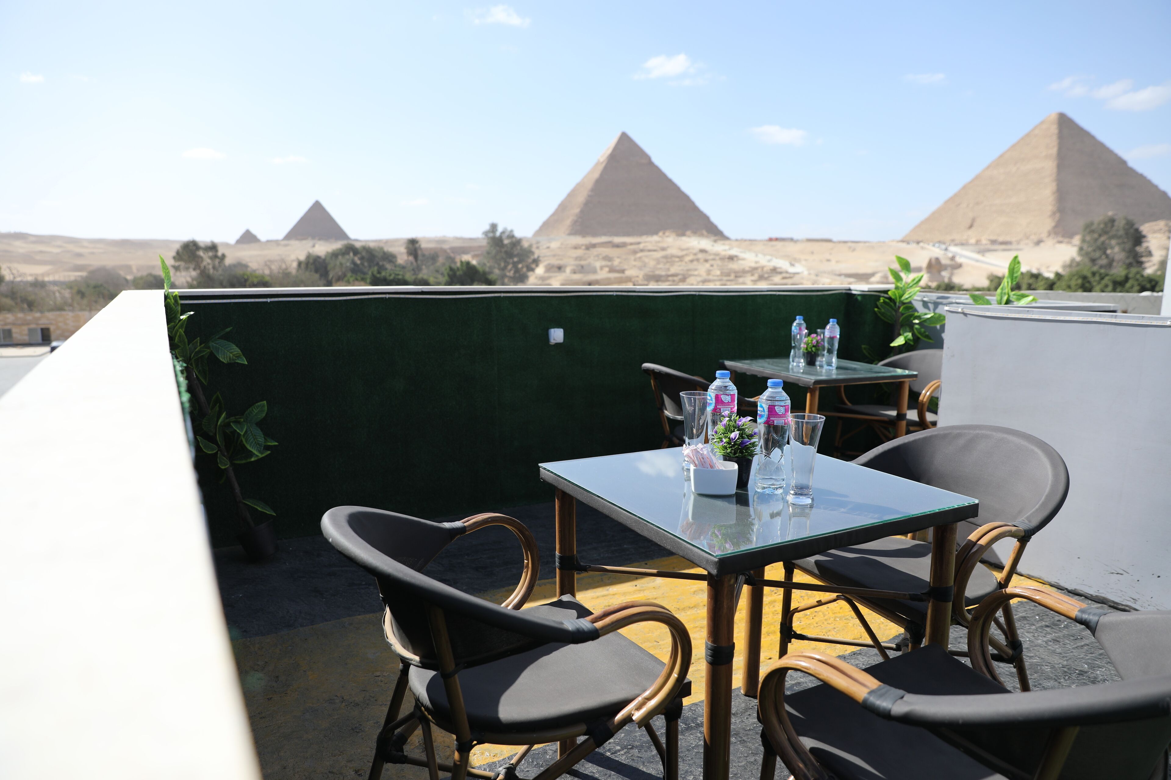 Terraza en la azotea con una mesa dispuesta para dos, con vistas a las pirámides al fondo.