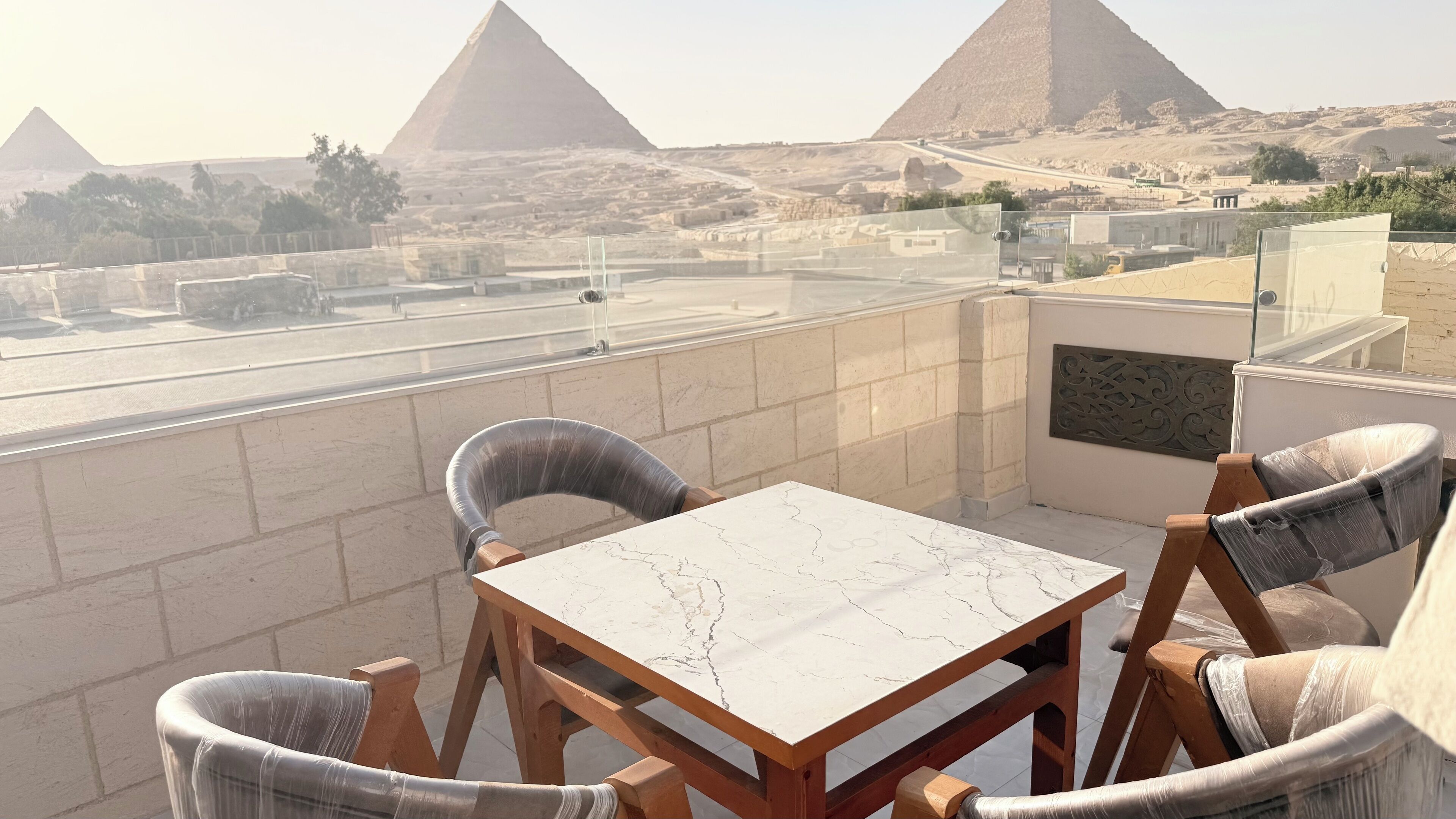A balcony with a table and chairs overlooking the pyramids.