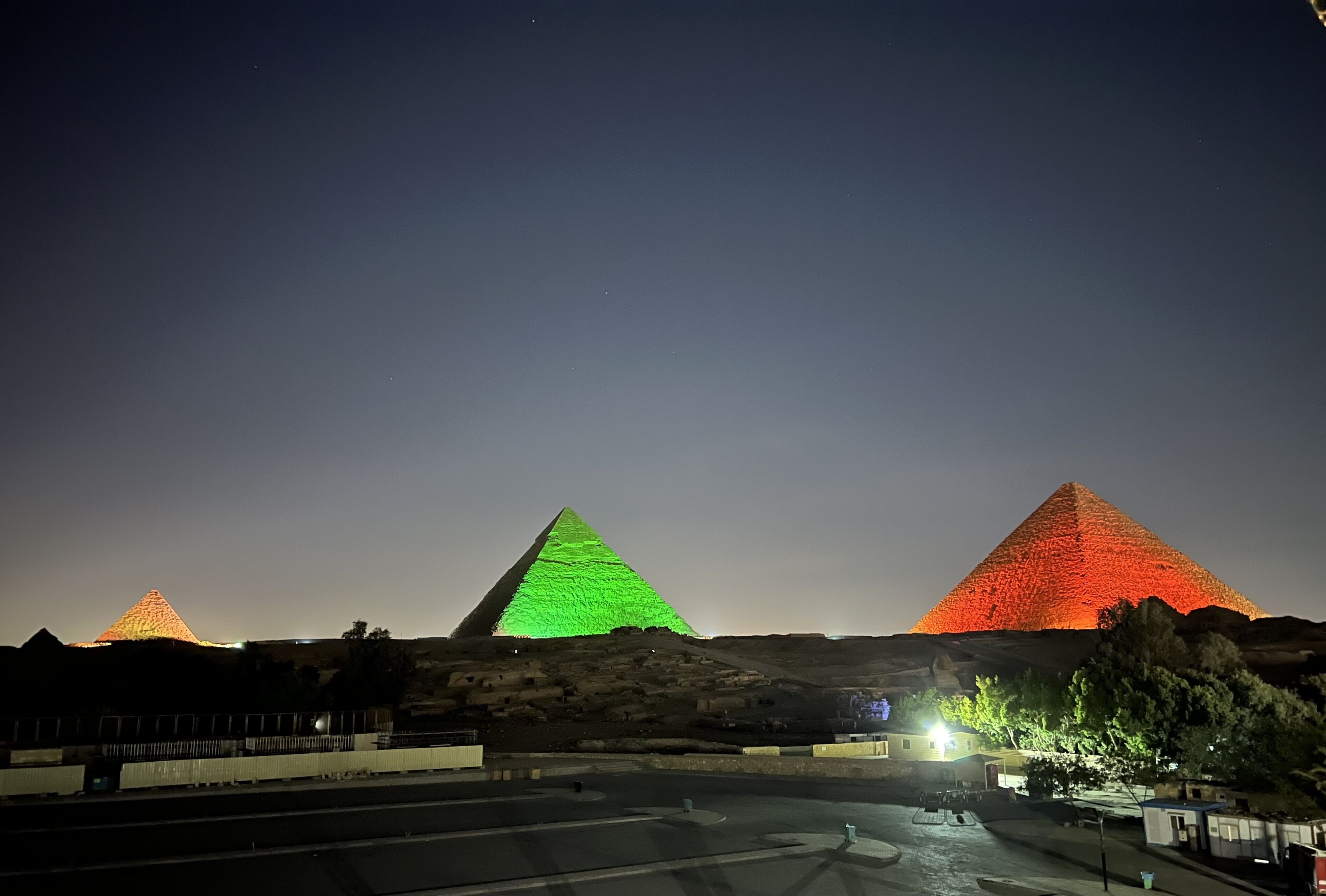 Trois pyramides illuminées la nuit.