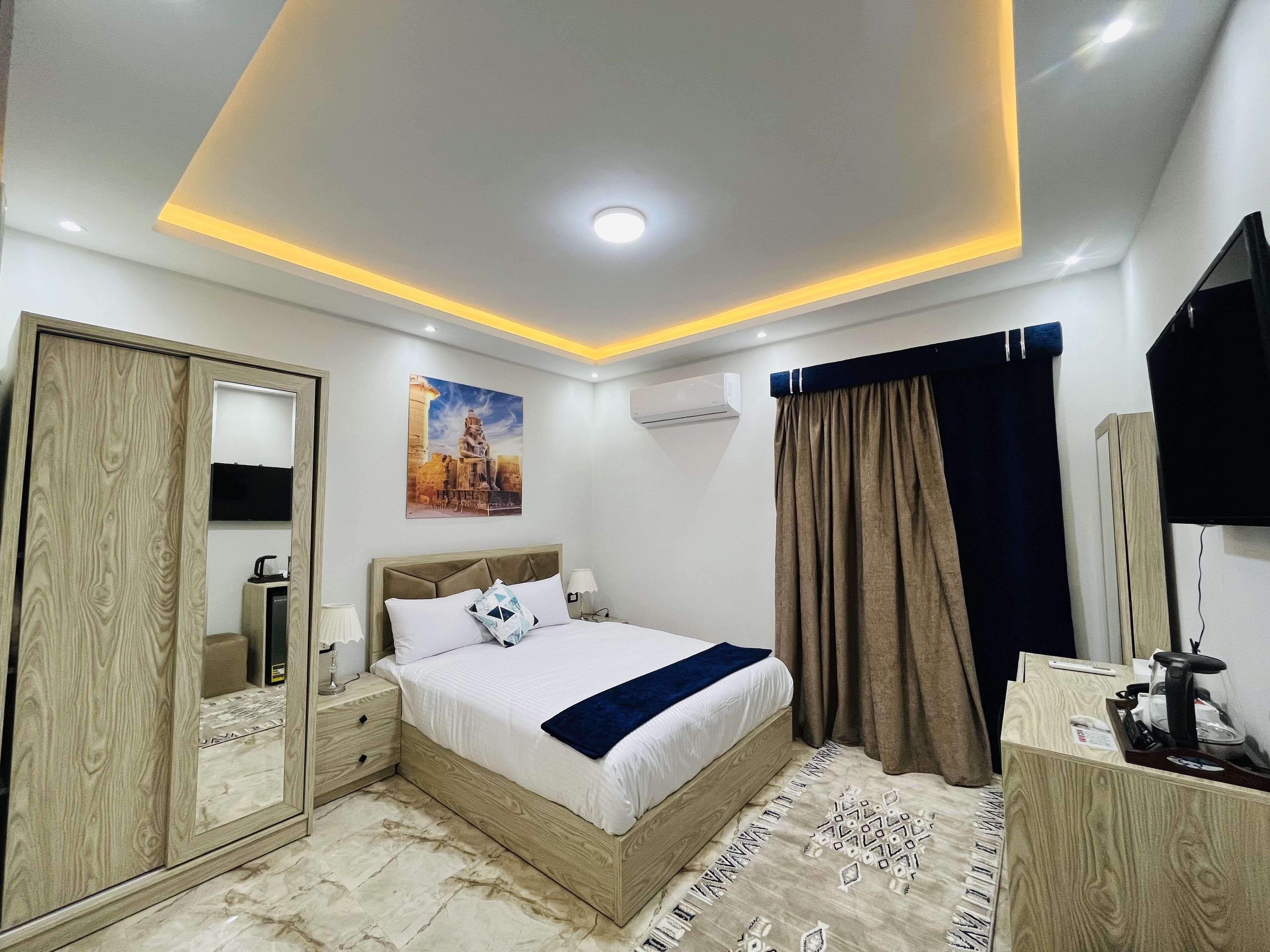 Un dormitorio moderno con cama, mesitas de noche, armario, televisor de pantalla plana y lámpara de techo.