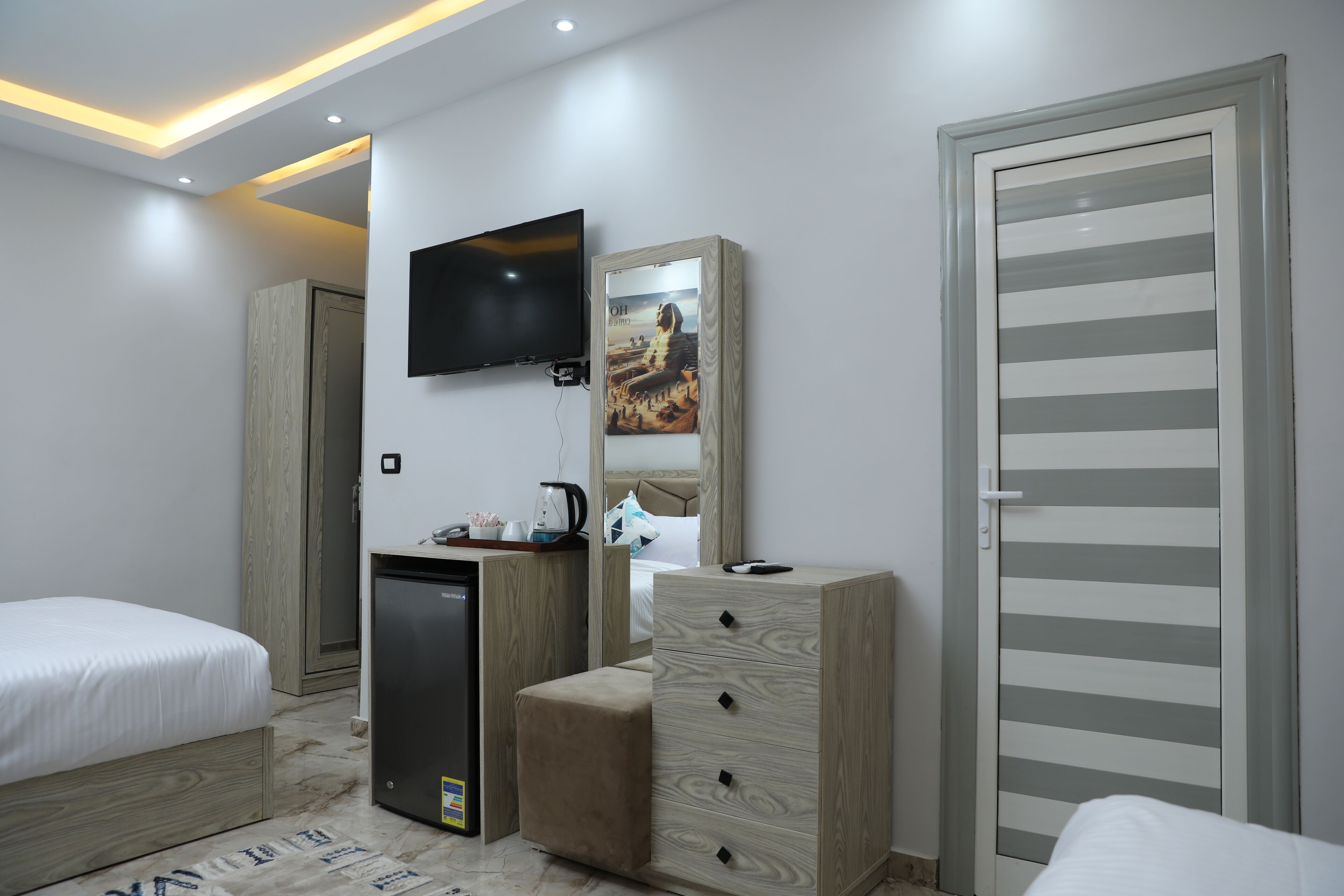 Une chambre moderne avec un lit, un bureau, une télévision et une armoire.