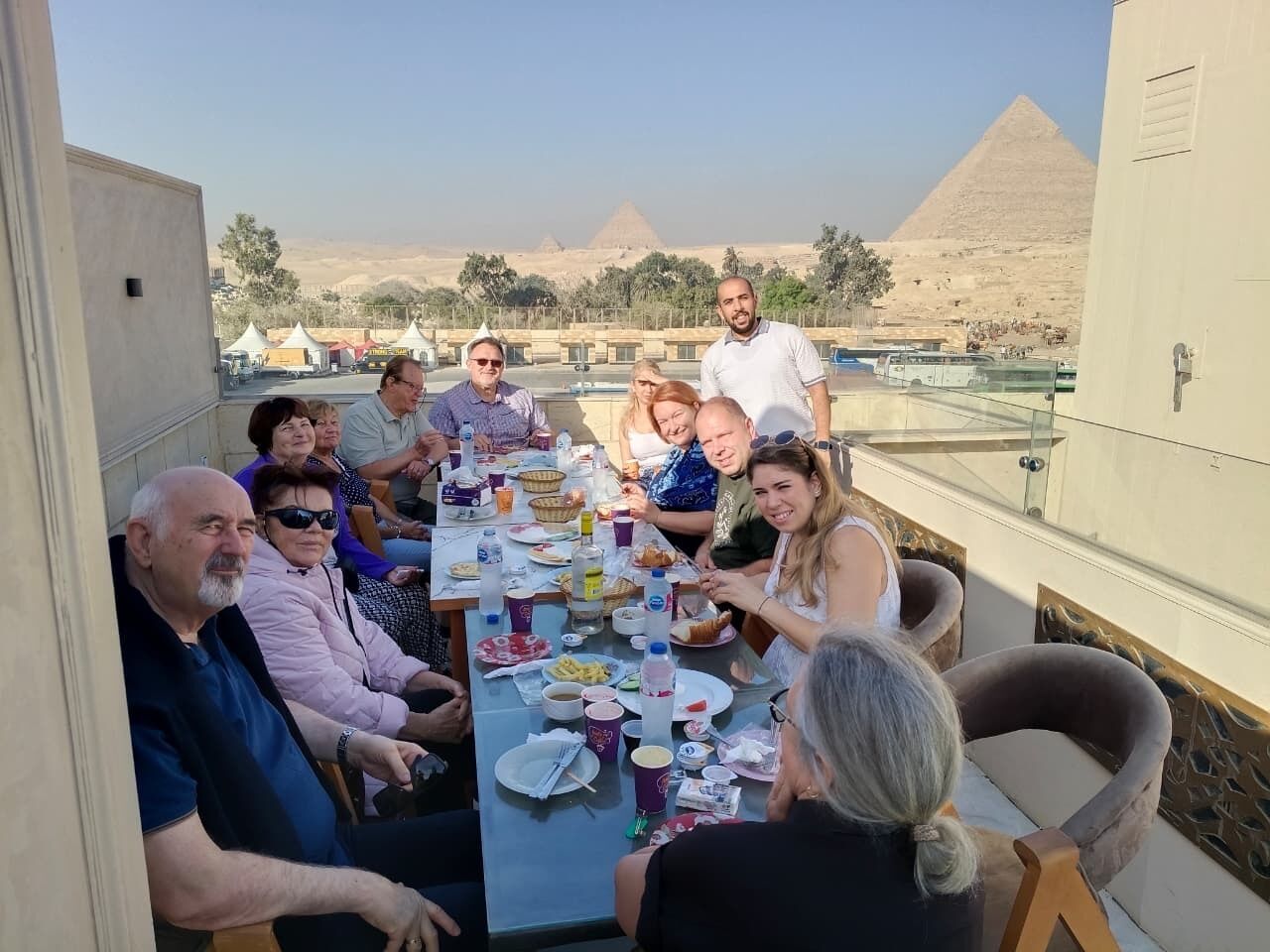 Un grupo de personas cenando en una mesa con vista a las pirámides.