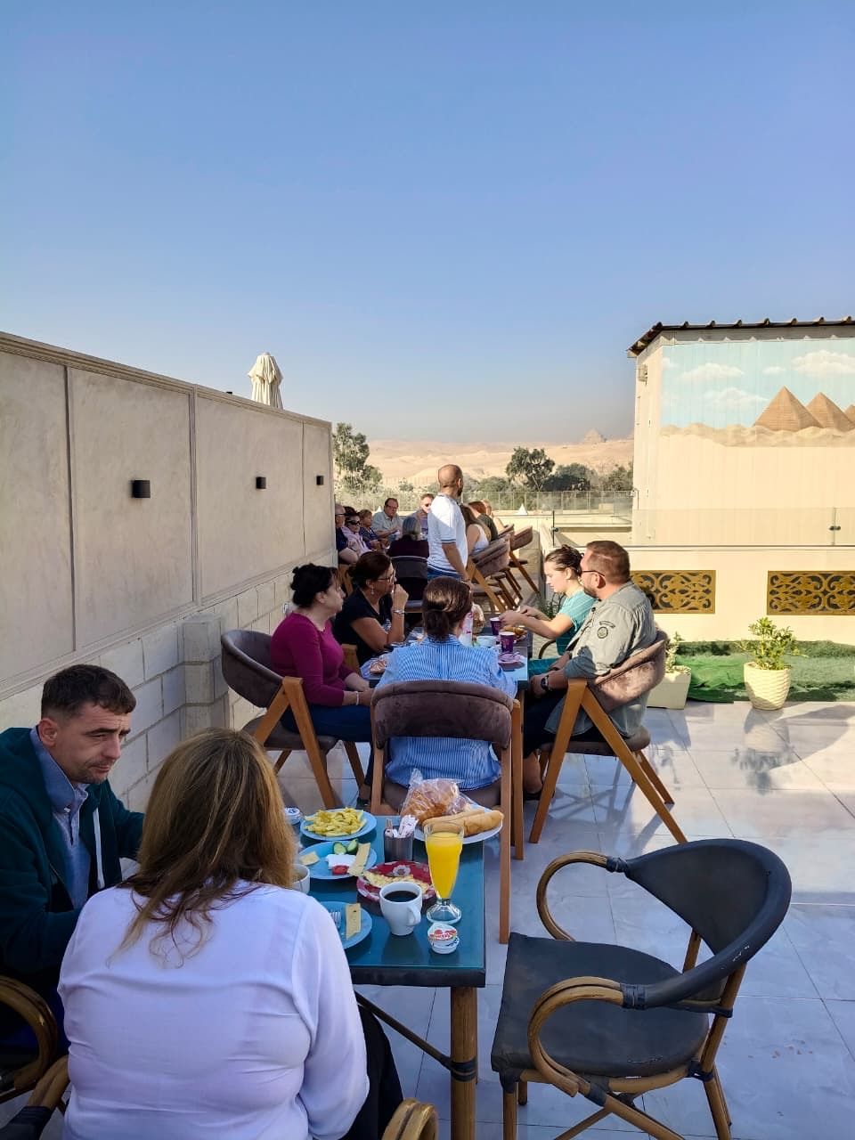A group of people dining outdoors with a view of pyramids in the background.