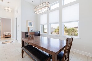 Un comedor amplio con una gran mesa de madera, bancos e iluminación colgante.