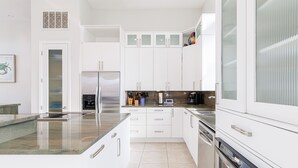 A modern kitchen with white cabinetry, a stainless steel refrigerator, and a built-in oven. - Del Sol-Outdoor Oasis with Pool and Hot Tub (Pensacola)