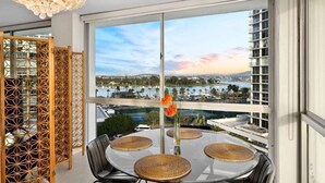 A balcony with a glass table, chairs, and a decorative vase with flowers.