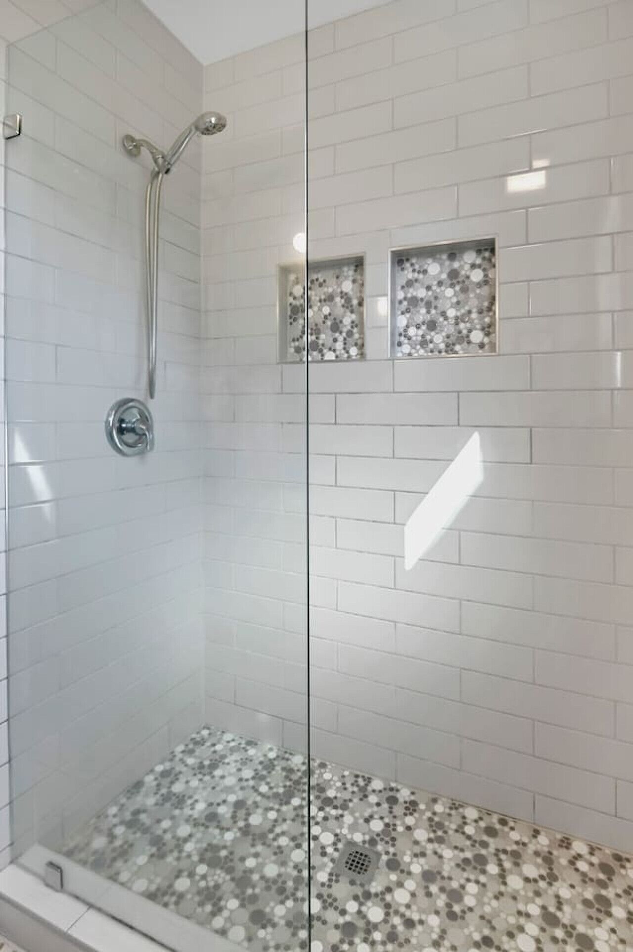 Ducha con paredes de vidrio, piso de baldosas y ducha.