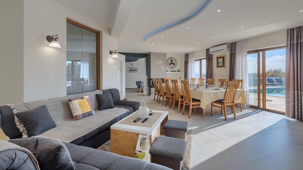 A modern living room with a sofa, coffee table, and dining area with chairs and a table.