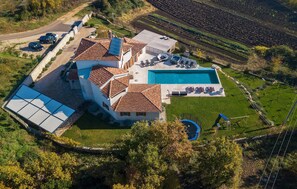 Relax on the spacious outdoor deck with a hot tub and lounge chairs, surrounded by serene terraced fields and a well-maintained lawn.