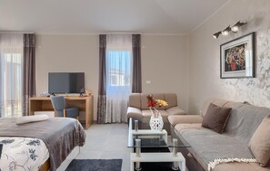 Relax in this stylish living room with a large flat-screen TV, comfortable sofa, and a beautiful bed.