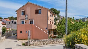A two-story building with a stone wall entrance, a satellite dish, and a private parking sign.