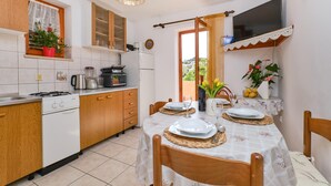 A kitchen with wooden cabinets, a gas stove, and a dining area with a table set for two.