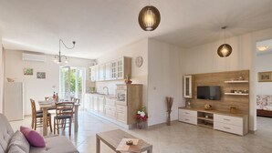 A spacious living area with a dining table, sofa, and kitchen area with cabinets and a TV. - Cozy apartment in Umag with private swimming pool, can be inside or outside (Umag)