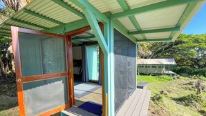 A small, open-air structure with a wooden door and a bench. - Pueo Cabin with Shared Bath and Common House (Kealakekua)