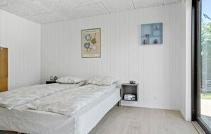 A bedroom with a bed, a nightstand, a shelf with decorative items, and a poster on the wall. - Beautiful home in Odder with WiFi (Odder)