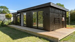 A modern wooden cabin with large sliding glass doors, a wooden deck, and a small outdoor shower. - Beautiful home in Odder with WiFi (Odder)