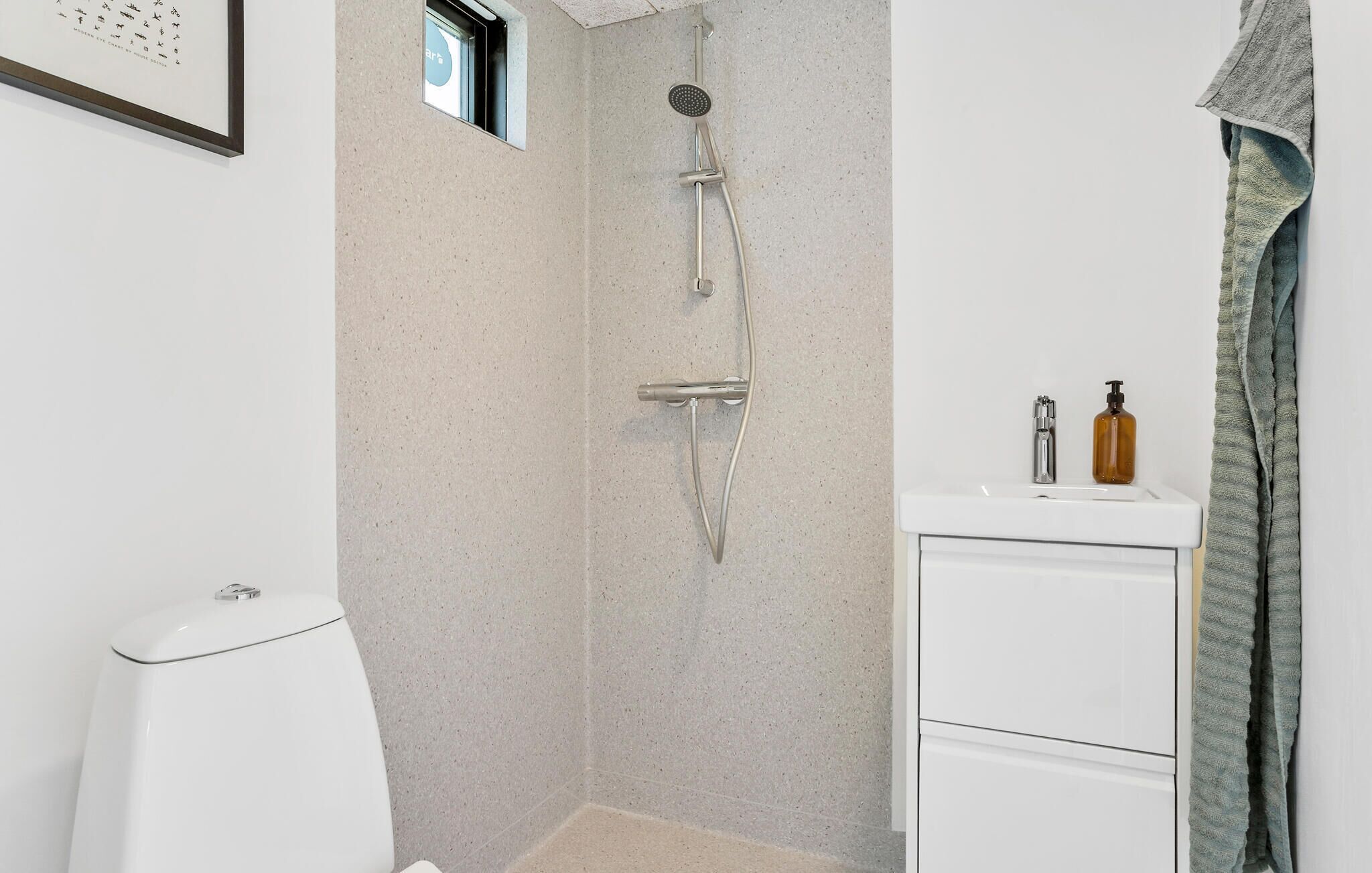 A bathroom with a shower, toilet, sink, and towel rack.