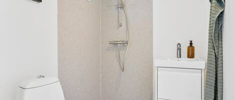 A bathroom with a shower, toilet, sink, and towel rack.