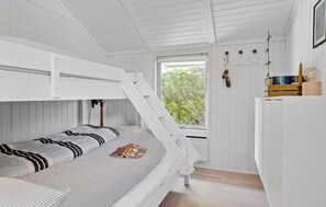A bunk bed room with a window, wooden walls, and a small desk with books and a lamp. - Beautiful home in Odder with WiFi (Odder)