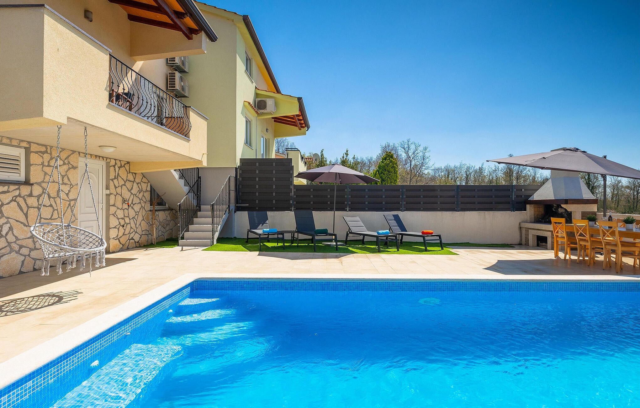 A swimming pool with lounge chairs and a barbecue area.