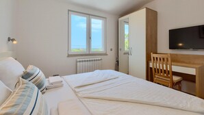 Ein Schlafzimmer mit einem Bett, einem Schreibtisch, einem Stuhl, einem Fernseher und einem Fenster mit Blick.