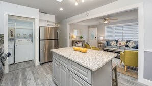 A modern kitchen with a central island, built-in appliances, and a dining area with a sofa and chairs. - Arcade · Firepit · 2 King Beds + Workspace (Stuart)