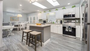 A modern kitchen with white cabinets, stainless steel appliances, and a central island with stools. - Arcade · Firepit · 2 King Beds + Workspace (Stuart)