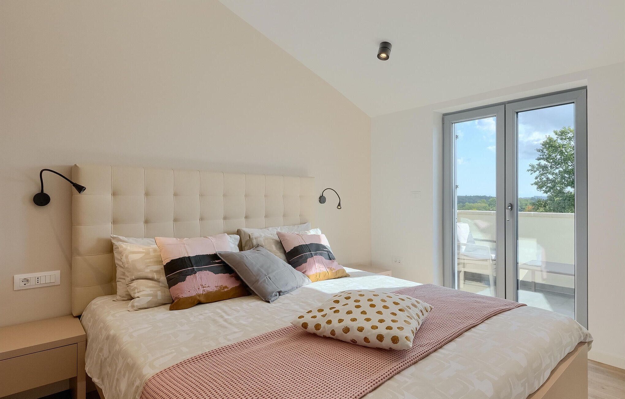 A bedroom with a large bed, a window with a view, and a ceiling light.