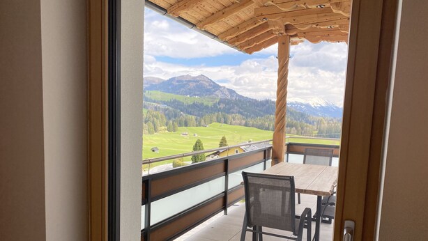 Un balcone con una pergola in legno, un tavolo e due sedie.