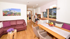Un soggiorno moderno con un divano, un tavolo da pranzo con sedie e una zona cucina con una finestra.