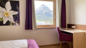 Una camera da letto con un letto, una scrivania e una finestra con tende.