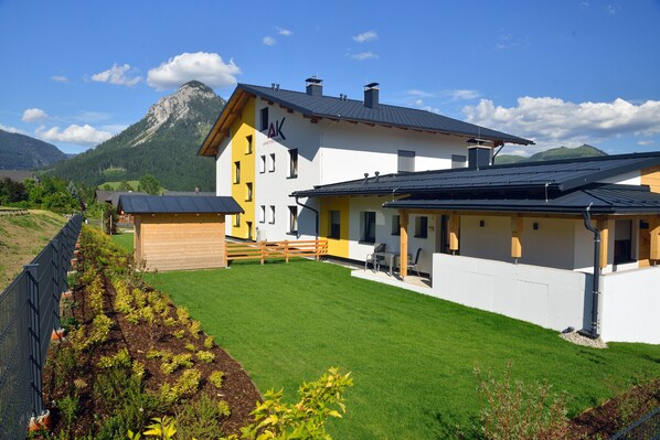 A two-story house with a yellow and white exterior, a covered patio, and a mountain in the background.