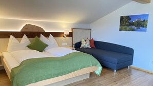 A modern bedroom with a bed, a sofa, and a painting on the wall. - Appartement Grimming - Kolb (Tauplitz)