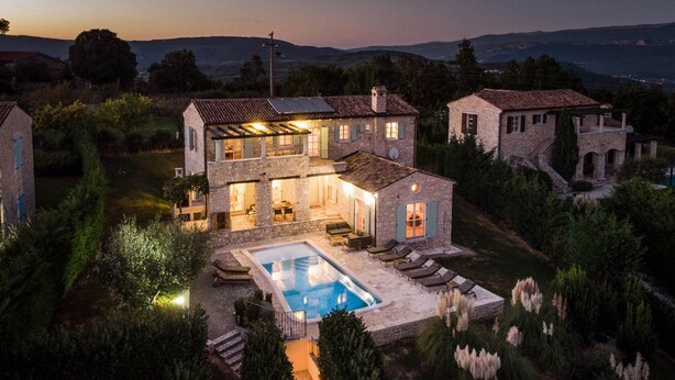 Une maison en pierre à deux étages, dotée d’une piscine, d’un espace extérieur aménagé et offrant une vue sur le paysage environnant.