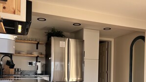 A modern kitchen with a stainless steel refrigerator, wooden flooring, and white cabinetry. - Beach Bunker Minute Walk To Beach and Pier at Old Orchard Family-Friendly Cozy (Old Orchard Beach)