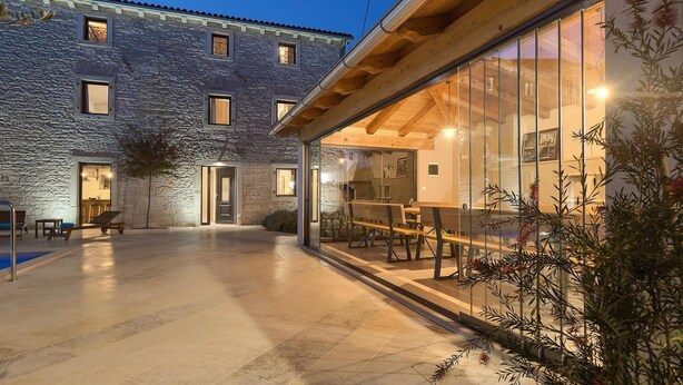 Un bâtiment en pierre doté d’un patio vitré, d’un espace extérieur aménagé pour s’asseoir et d’une piscine.