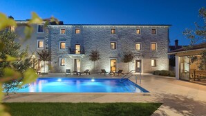 Un bâtiment doté d’une piscine, d’un espace extérieur aménagé et d’une façade en pierre.