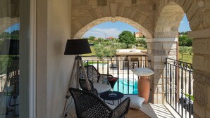 Ein Balkon mit Pool, Steinbögen, Korbmöbeln und einer Lampe.