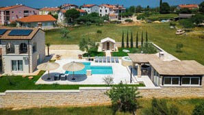 Eine moderne Villa mit Swimmingpool, Sitzgelegenheiten im Freien und einer Steinmauer.