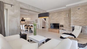Ein modernes Wohnzimmer mit Kamin, Essbereich und einer Küche im Hintergrund.