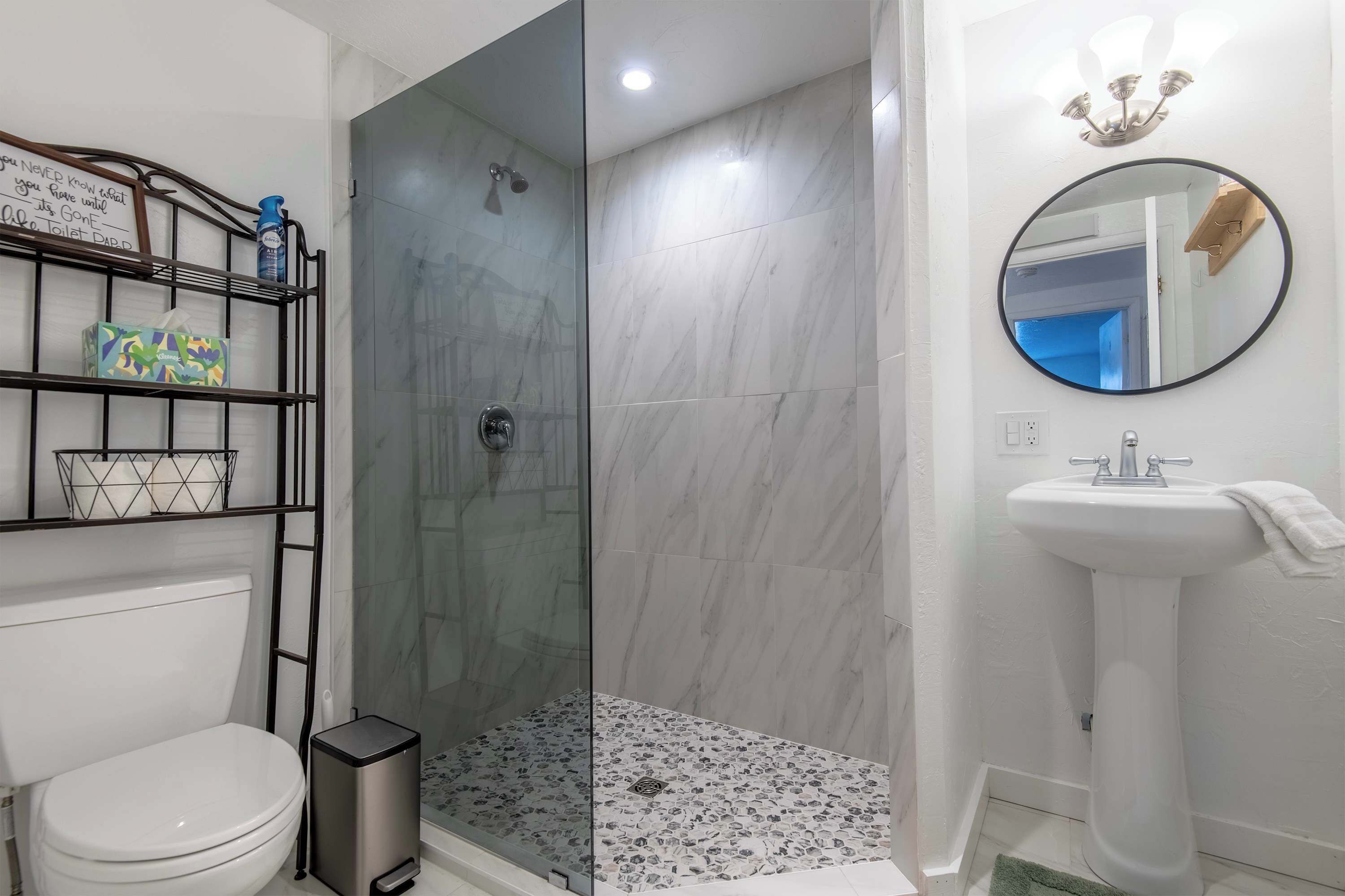 Un baño con ducha de vidrio, inodoro, lavamanos y espejo.