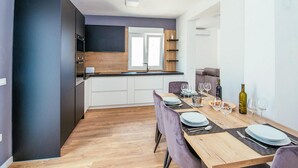 Une cuisine moderne avec des meubles de couleur sombre, un plan de travail en bois et un four encastré.