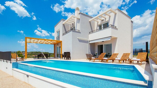 Un bâtiment à deux étages doté d’une piscine, d’un espace extérieur aménagé et d’une pergola.