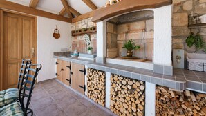 A rustic kitchen with a stone wall, wooden beams, and a built-in wood storage unit. - Beautiful home in Porec (Porec)