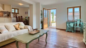 A cozy living room with a sofa, a coffee table, and a desk with drawers. There is a dining area with chairs and a table, and a kitchen area with cabinets and a countertop. - Beautiful home in Porec (Porec)