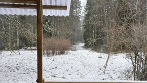 Eine verschneite Waldszene, im Vordergrund eine Holzhütte.