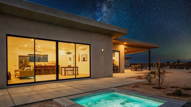 Een modern huis met een zwembad, grote glasramen en een terras.