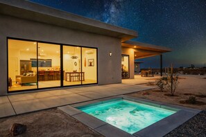 Une maison moderne dotée d’une piscine, de grandes baies vitrées et d’un espace patio.